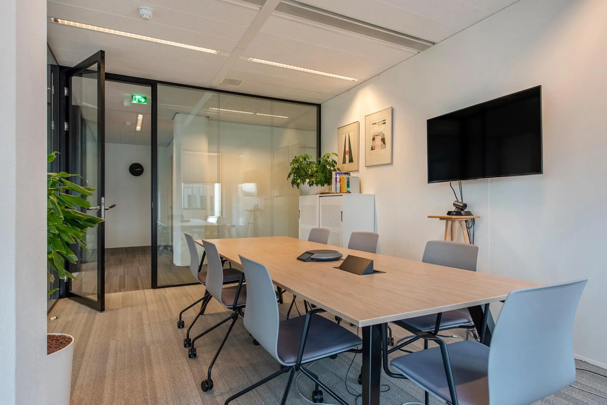 Moderne vergaderruimte aan de Grote Marktstraat met glazen wanden, een grote tafel, stoelen, een flatscreen en kantoorplanten.